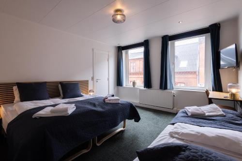a bedroom with two beds and two windows at Milling Hotel Mini 19 in Odense