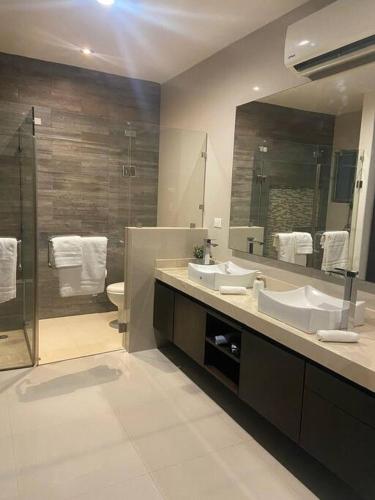 a bathroom with two sinks and a shower and a mirror at Residencia Campo Golf Altozano in Villahermosa