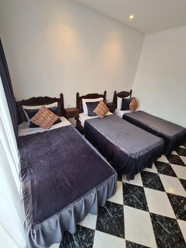 two beds in a room with a checkered floor at Maison d'hôte Bousaid in Chefchaouene