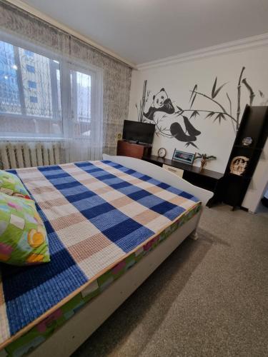 a bedroom with a bed with a checkered blanket at Panda flat in Astana