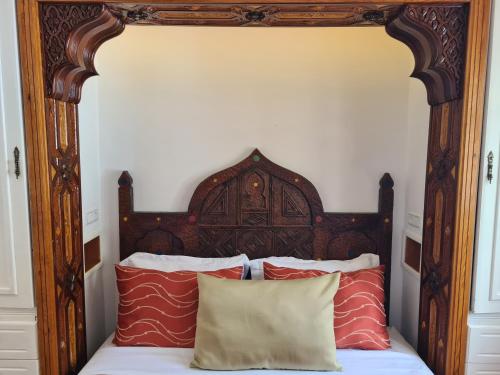 a bed with an ornate wooden headboard and pillows at Maison d'hôte Bousaid in Chefchaouene