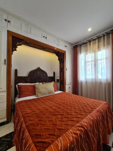 a bedroom with a large bed with an orange bedspread at Maison d'hôte Bousaid in Chefchaouene