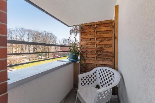 einen weißen Stuhl auf einem Balkon mit einem Fenster in der Unterkunft Grobla Centrum 3 by Grand Apartments in Danzig