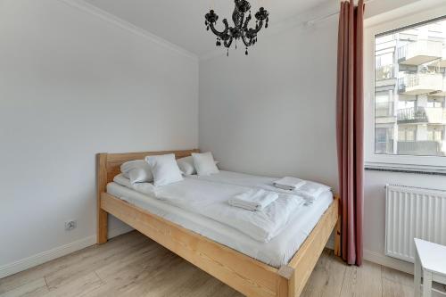 Schlafzimmer mit einem Bett mit weißer Bettwäsche und einem Fenster in der Unterkunft Grobla Centrum 3 by Grand Apartments in Danzig