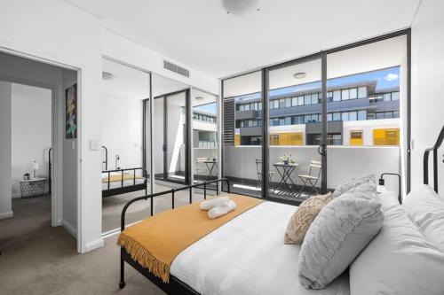 a bedroom with a large bed and a balcony at NEW 3BR Apt in Kingsgrove Sleeps 7 in Sydney