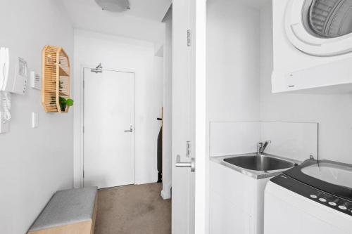 a white bathroom with a sink and a door at NEW 3BR Apt in Kingsgrove Sleeps 7 in Sydney