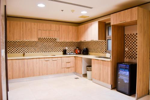 uma cozinha com armários de madeira e um frigorífico preto em Stylish and private apartment em Riyadh