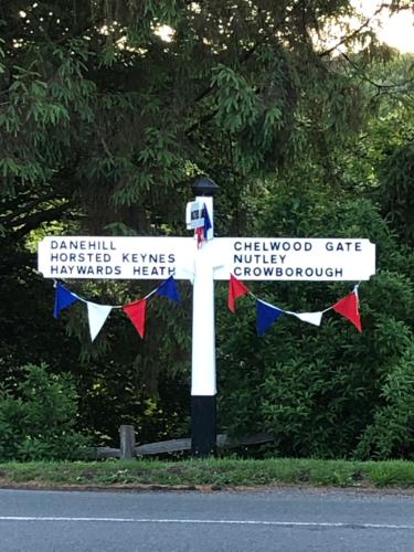 a white cross with signs on the side of a road at The Nest Danehill in Haywards Heath