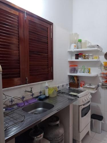 a kitchen with a sink and a stove at CHALE PERTO DA PRAIA COM DUAS SUITES E VARANDAO in Pacatuba