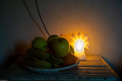 a bowl of apples and bananas next to a light at Siwa Palace Lodge in Siwa