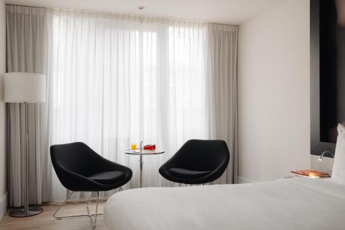 a hotel room with two black chairs and a bed at Leonardo Boutique Hotel Maastricht City Center in Maastricht
