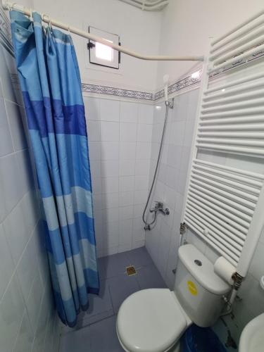 a bathroom with a toilet and a blue shower curtain at Maison d'hôte Bousaid in Chefchaouene