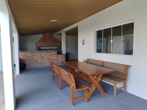 a wooden table and chairs on a patio with a fireplace at Linda Casa Jardim - 500 Mts da Praia in Navegantes