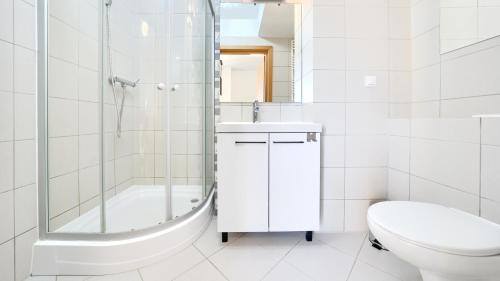 a white bathroom with a shower and a toilet at Promenada I, Sun & Snow in Świnoujście