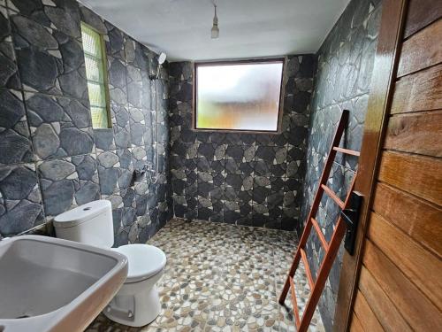 ein Bad mit einem WC, einem Waschbecken und einem Fenster in der Unterkunft UmaUthu Bali in Tabanan