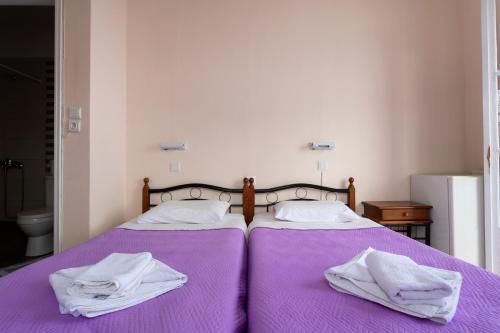 a bedroom with two beds with purple sheets and towels at Stelios Hotel in Spetses