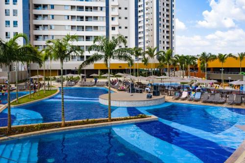 a large swimming pool with palm trees and buildings at Ideal para famílias, hospede-se no Solar das Águas. in Olímpia