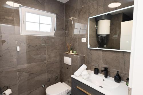 a bathroom with a sink and a toilet and a mirror at Apartment MM in Sukošan