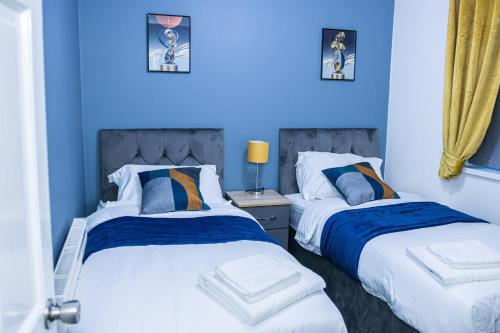 two beds in a bedroom with blue walls at Impeccable 4-Bed House in Telford West Midlands in Telford