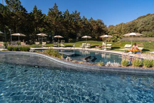 una piscina en un patio con sillas y sombrillas en Stella del Mare Family Camping Village, en Castiglione della Pescaia