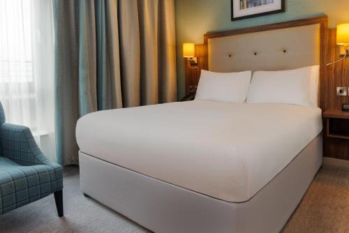 a bedroom with a large white bed and a chair at DoubleTree by Hilton London Angel Kings Cross in London