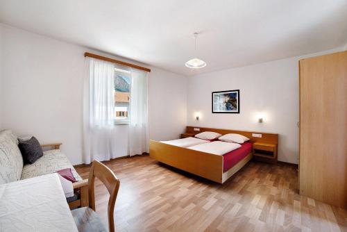 een slaapkamer met een bed en een bank bij Fröhlichhof Wohnung Apfelblüte in Lagundo