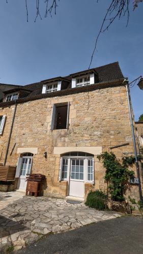 - un bâtiment en briques avec une porte et des fenêtres blanches dans l'établissement Kingfisher Cottage, à Castelnaud-la-Chapelle