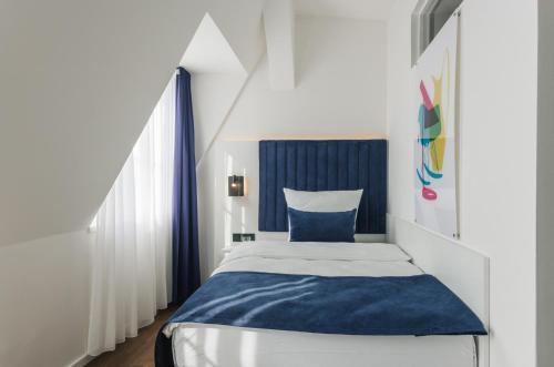 a small bedroom with a blue and white bed at Homaris East Side Hotel - Mobile Key Access in Berlin