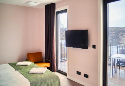 1 dormitorio con 1 cama, TV y balcón en HOTEL PORTOMARÍN STAR en Portomarin
