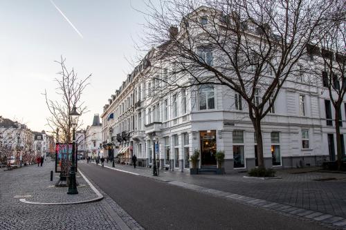 a city street with white buildings and trees on the street at Designhotel Maastricht in Maastricht