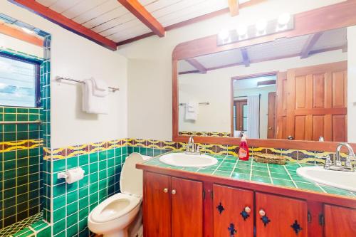 a bathroom with a toilet and a sink and a mirror at Condo #25 @ Beachside Villas in Placencia Village