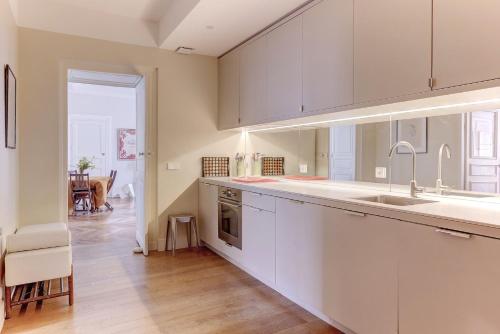 une grande cuisine avec des placards blancs et un évier dans l'établissement La Cathédrale - Versailles, à Versailles