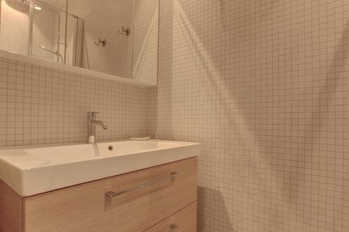 une salle de bain blanche avec un lavabo et un miroir dans l'établissement La Cathédrale - Versailles, à Versailles