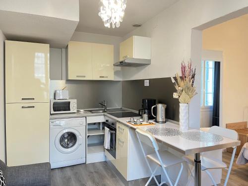 - une cuisine avec un évier et une table avec un lave-linge dans l'établissement Résidence Victoria, à Vichy