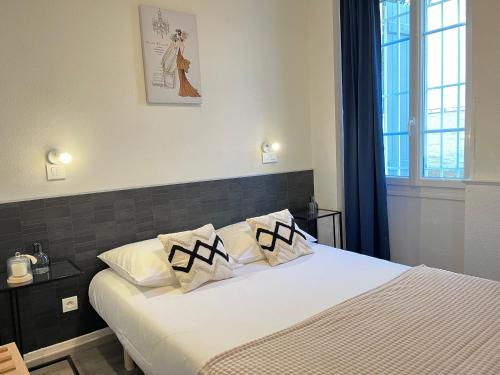 1 dormitorio con 1 cama con sábanas y almohadas blancas en Résidence Victoria, en Vichy