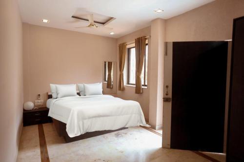 a bedroom with a white bed and a window at CORAL VILLA in Lonavala