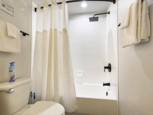 a bathroom with a white shower curtain and a toilet at 2BR Kierland Commons CozySuites by the golf course in Scottsdale