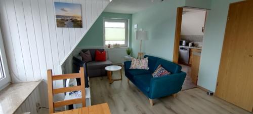 a living room with a blue couch and a chair at Schippkieker in Heikendorf