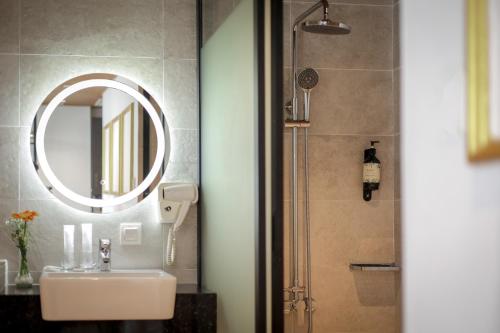 a bathroom with a sink and a mirror and a shower at Santa Grand Classic Kuala Lumpur, Chinatown in Kuala Lumpur