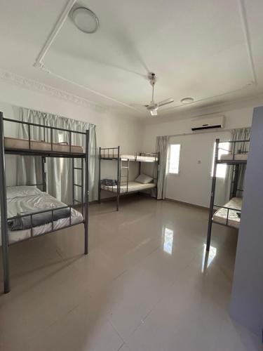 a room with three bunk beds and a room with a hallway at Basil Hostel in Muscat