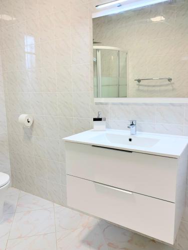 une salle de bain blanche avec un lavabo et un miroir dans l'établissement Campo Vecchio Kamerops et piscine, à Ghisonaccia