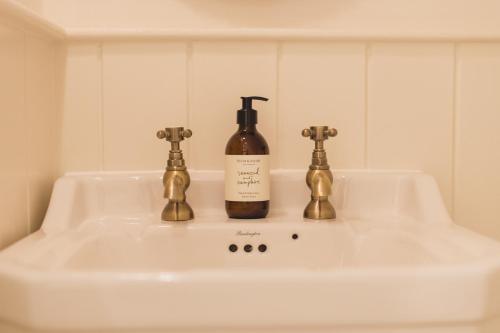 ein Waschbecken mit einer Flasche Wein drauf in der Unterkunft Buckingham Mews _ Rockpool Cottage 5 in Kent