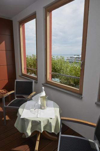 a table and chairs in a room with two windows at Flair Hotel zum Schiff in Meersburg