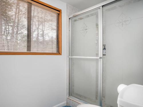 a bathroom with a shower and a toilet and a window at Hot Tub, Fire Pit & Fenced Yard w Resort Amenities in Hedgesville