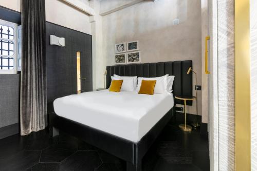 a bedroom with a large white bed with yellow pillows at Numa Florence Palazzo Moro in Florence