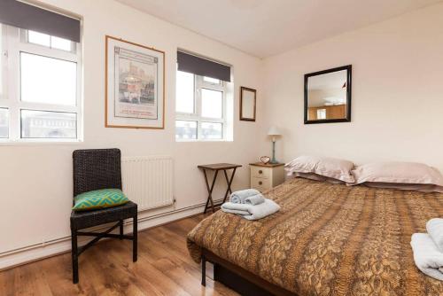 um quarto com uma cama grande e uma cadeira em Central Camden Flat With Terrace For 4 People em Londres