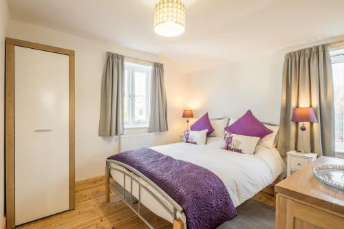 a bedroom with a bed with purple pillows and a sink at Beautiful and Spacious Cambridge Home with Free Parking & Garden! in Cambridge