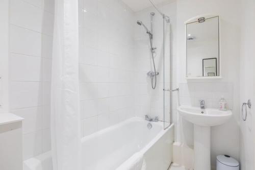 La salle de bains blanche est pourvue d'un lavabo, d'une baignoire et d'une douche. dans l'établissement Lovely 2 bedroom apartment - ideal location, à Cambridge