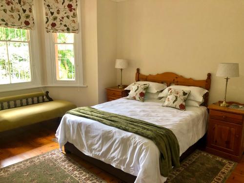 a bedroom with a bed with white sheets and pillows at Heritage Haven in Howick