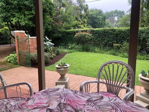a patio with a table and chairs and a garden at Heritage Haven in Howick